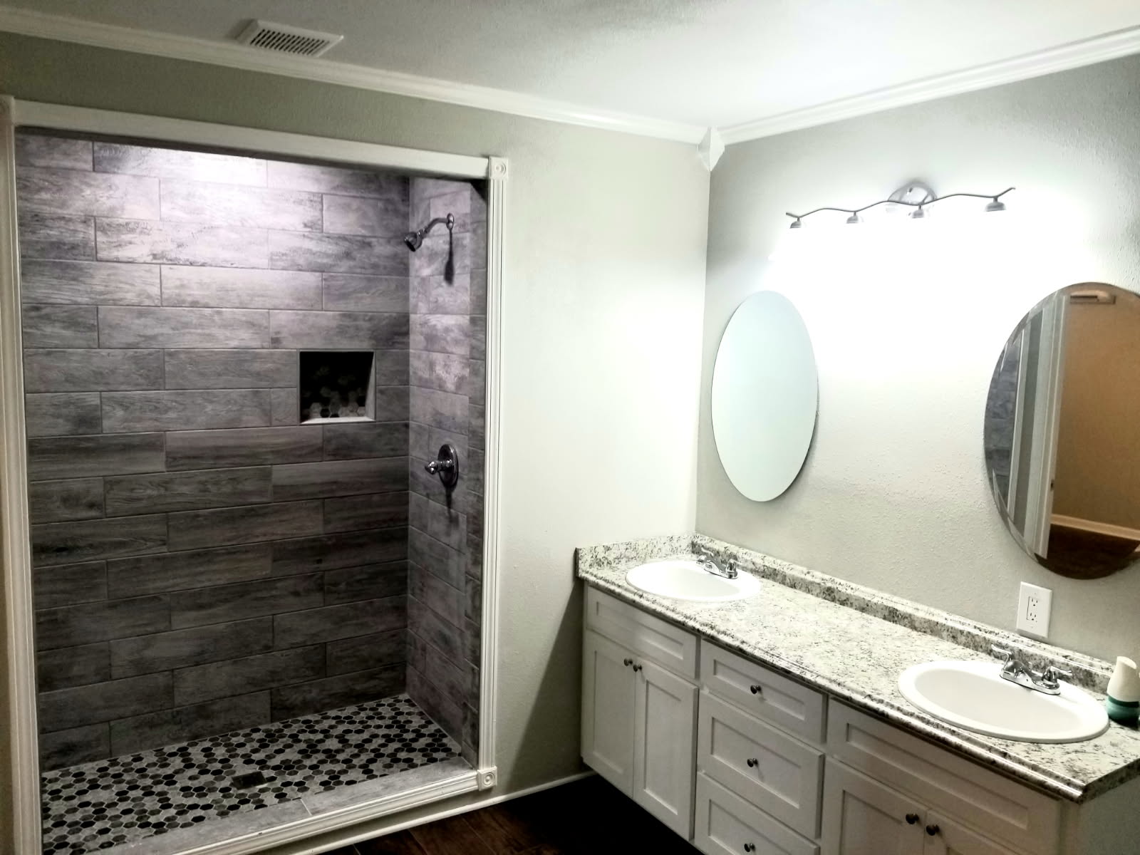 Remodeled master bathroom with walk-in tile shower and double granite vanity