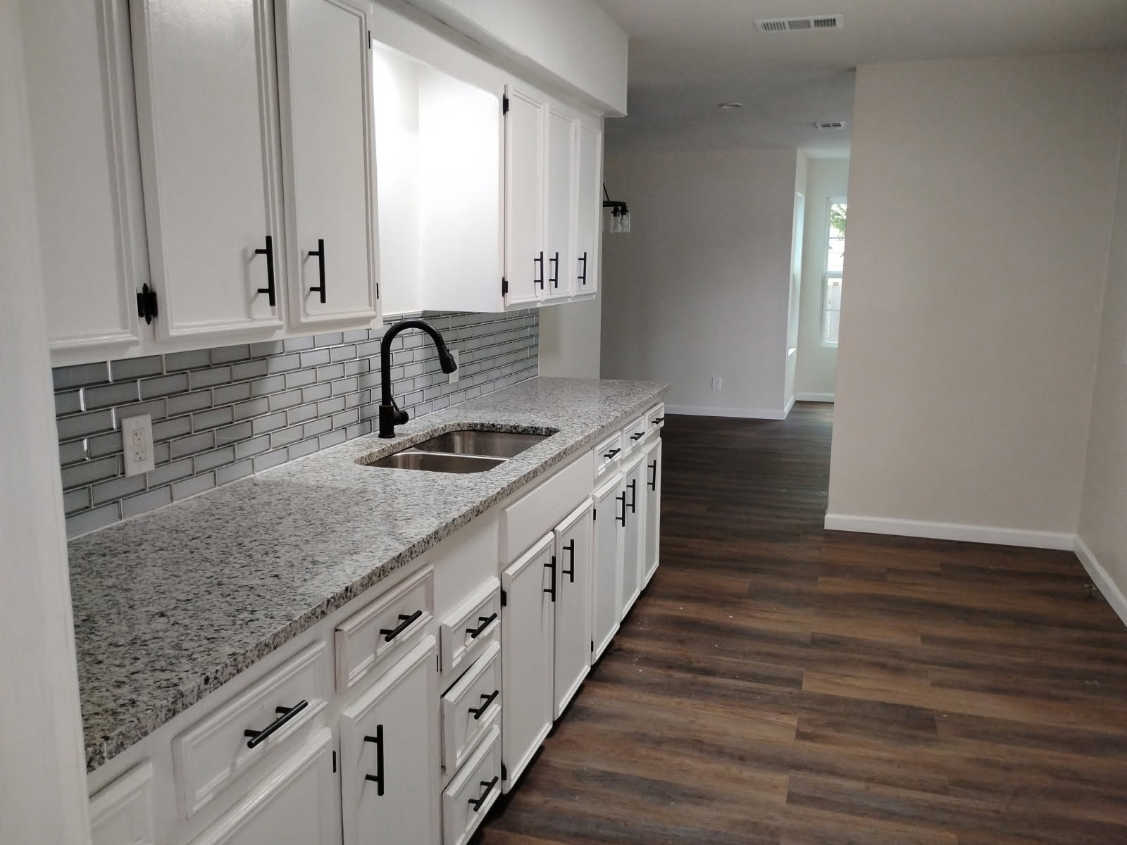 Remodeled galley kitchen opening to the living area, granite counters and new flooring