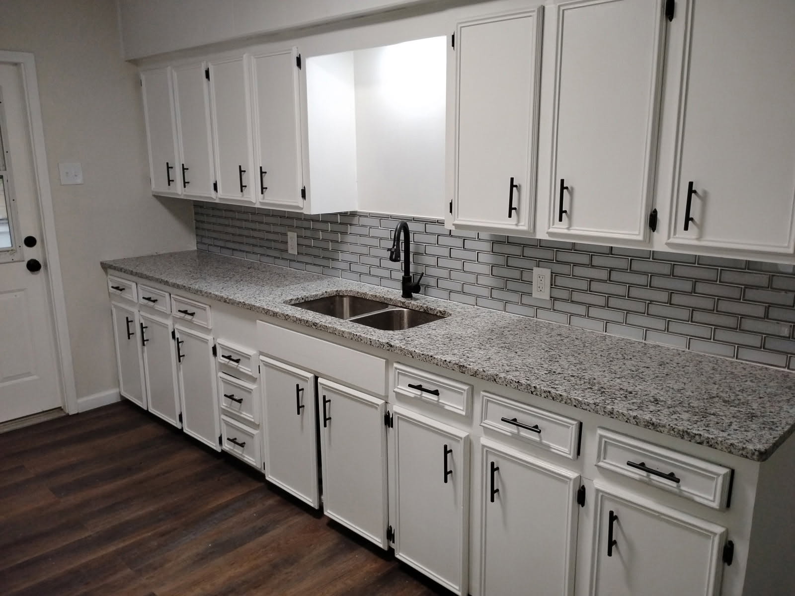 Remodeled kitchen with white cabinets, granite countertops and glass subway tile backsplash