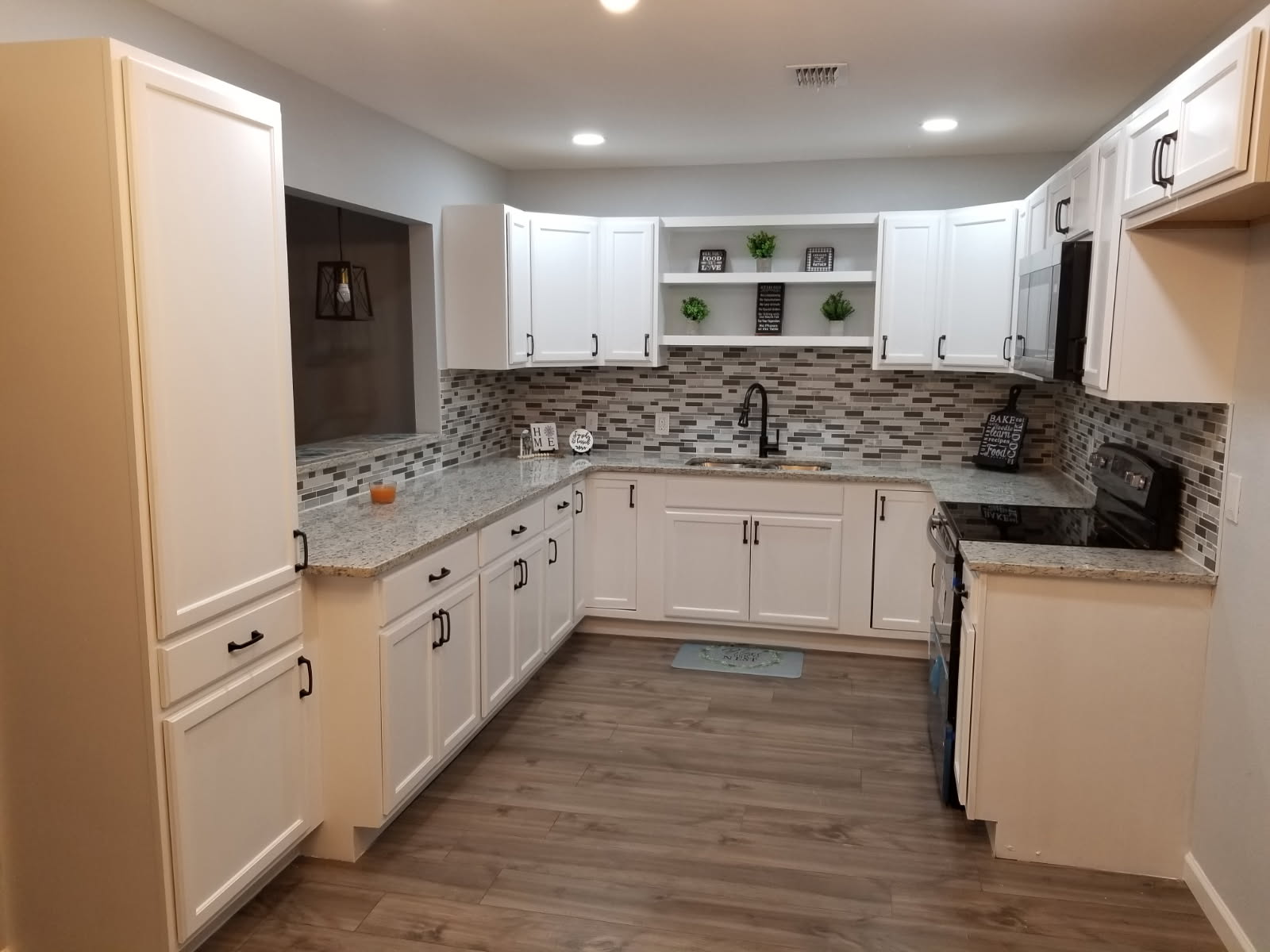 Remodeled U-shaped kitchen with white cabinets and mosaic tile backsplash