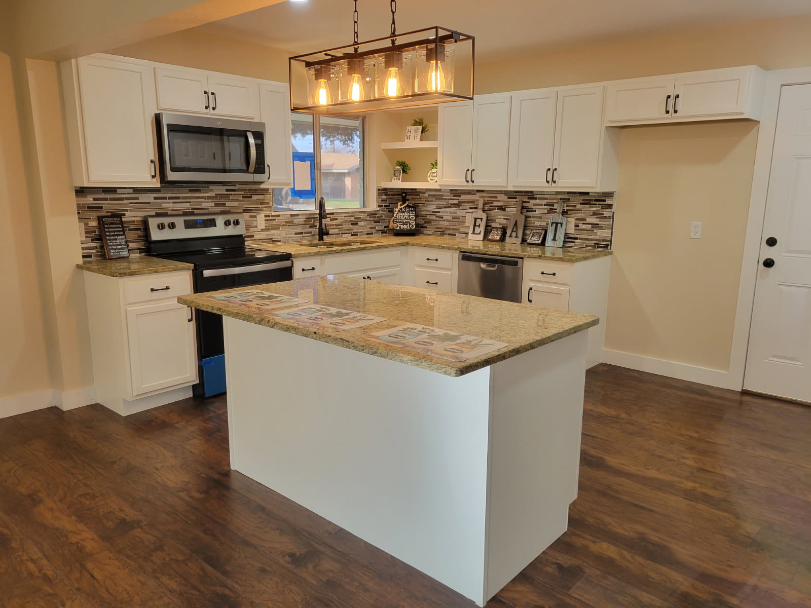Wide view of remodeled kitchen with island and pendant lighting